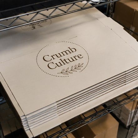 Custom bakery boxes in bulk flat-packed on a shelf